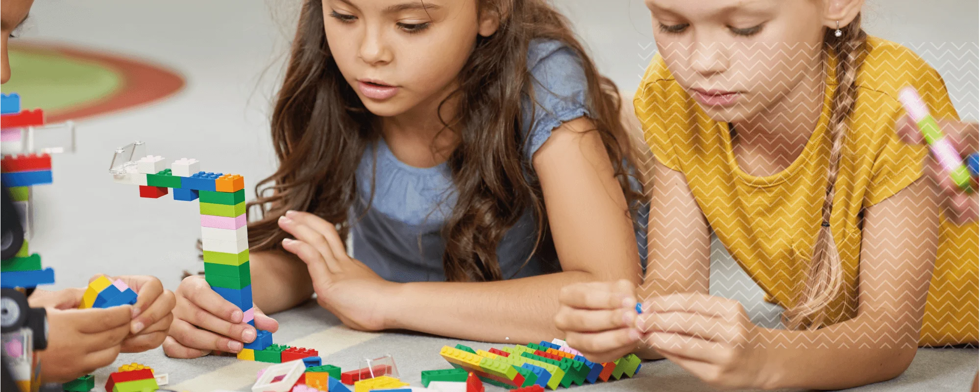 Niñas jugando con piezas de construcción como parte de una actividad de estimulación cognitiva infantil para desarrollar habilidades mentales y motoras.
